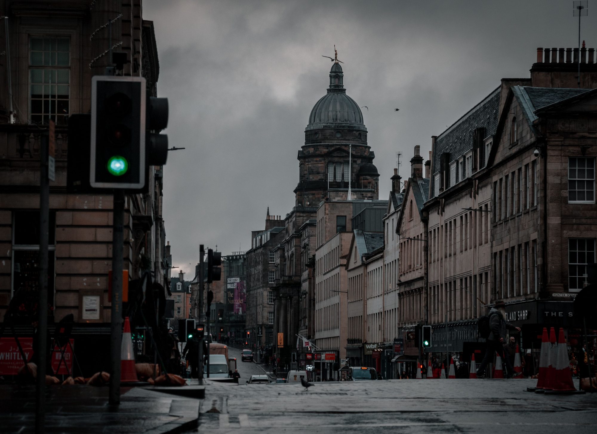 A rainy Edinburgh Old Town street with the Old College dome visible and slate roofs glistening with rain