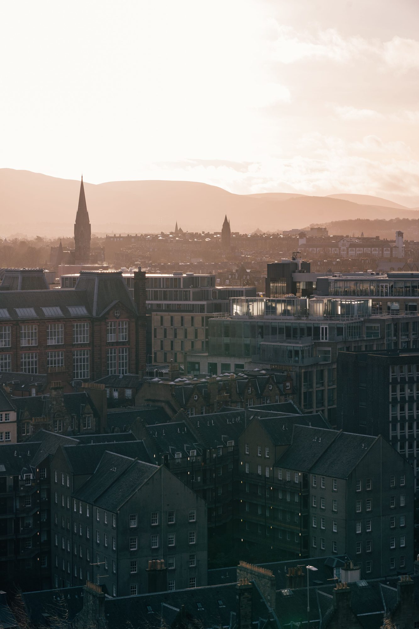 Sunset over the Edinburgh skyline, slate roofs and chimney stacks silhouetted against an orange sky